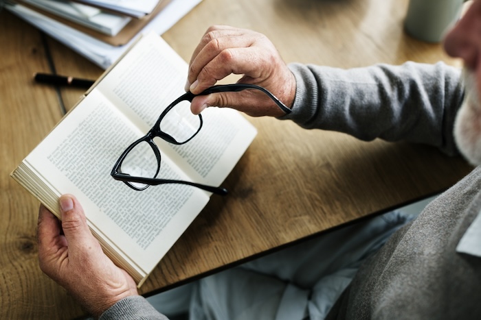 man reading a book and holding glasses